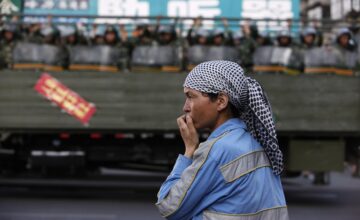 Chinese military police ride past a Uighur woman on main street in Urumqi, Xinjiang Uighur Autonomous Region, July 2009. (Nir Elias / Courtesy Reuters)
