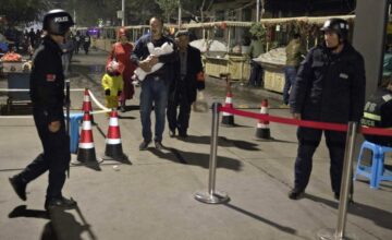FILE - Residents walk past a security checkpoint at the close of a open-air market in Kashgar in western China's Xinjiang region, Nov. 4, 2017. Authorities are using detentions in political indoctrination centers and surveillance in efforts to control the Xinjiang region and its Uighurs, a Turkic-speaking Muslim minority Beijing fears could be influenced by extremism.